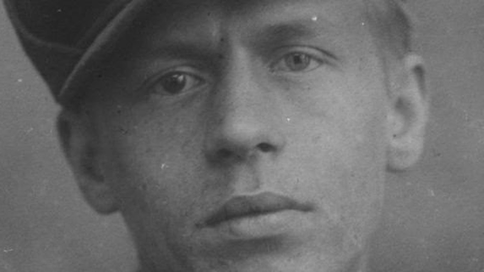 Kuvassa on Jalmari Ruokokosken kasvot musta-valkokuvassa. Hänellä on lippalakki päässään. Kuvan sävy on harmaa.