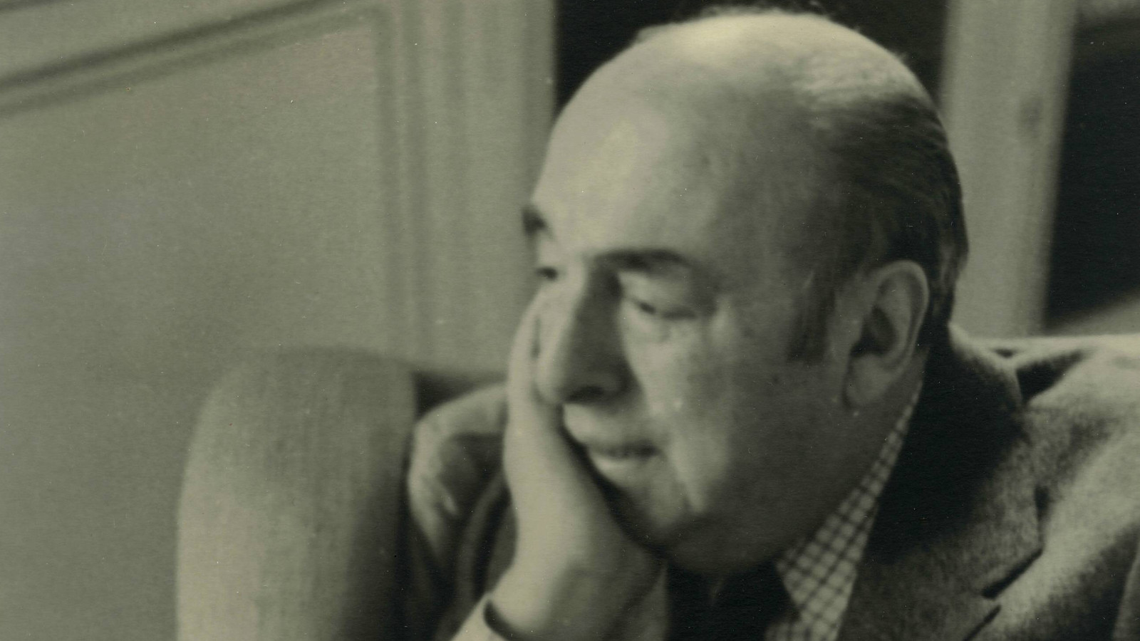 Kuvassa on Pablo Neruda istumassa sivuttain nojatuolissa ja oikea käsi poskellaan. Kuva on musta-valkoinen ja sävytetty ruskehtavaksi.