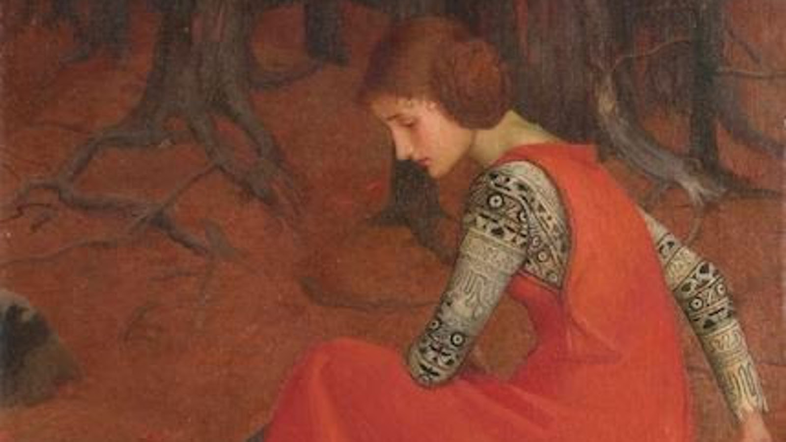 Kuvassa on nuori nainen istumassa ja on muratuneena sivuttain vasemmalla. Hänellä on punainen hihaton mekko ja mustan harmaan kirjava pusero. Taustalla punaisen ruskeaa maastoa ja oksia.