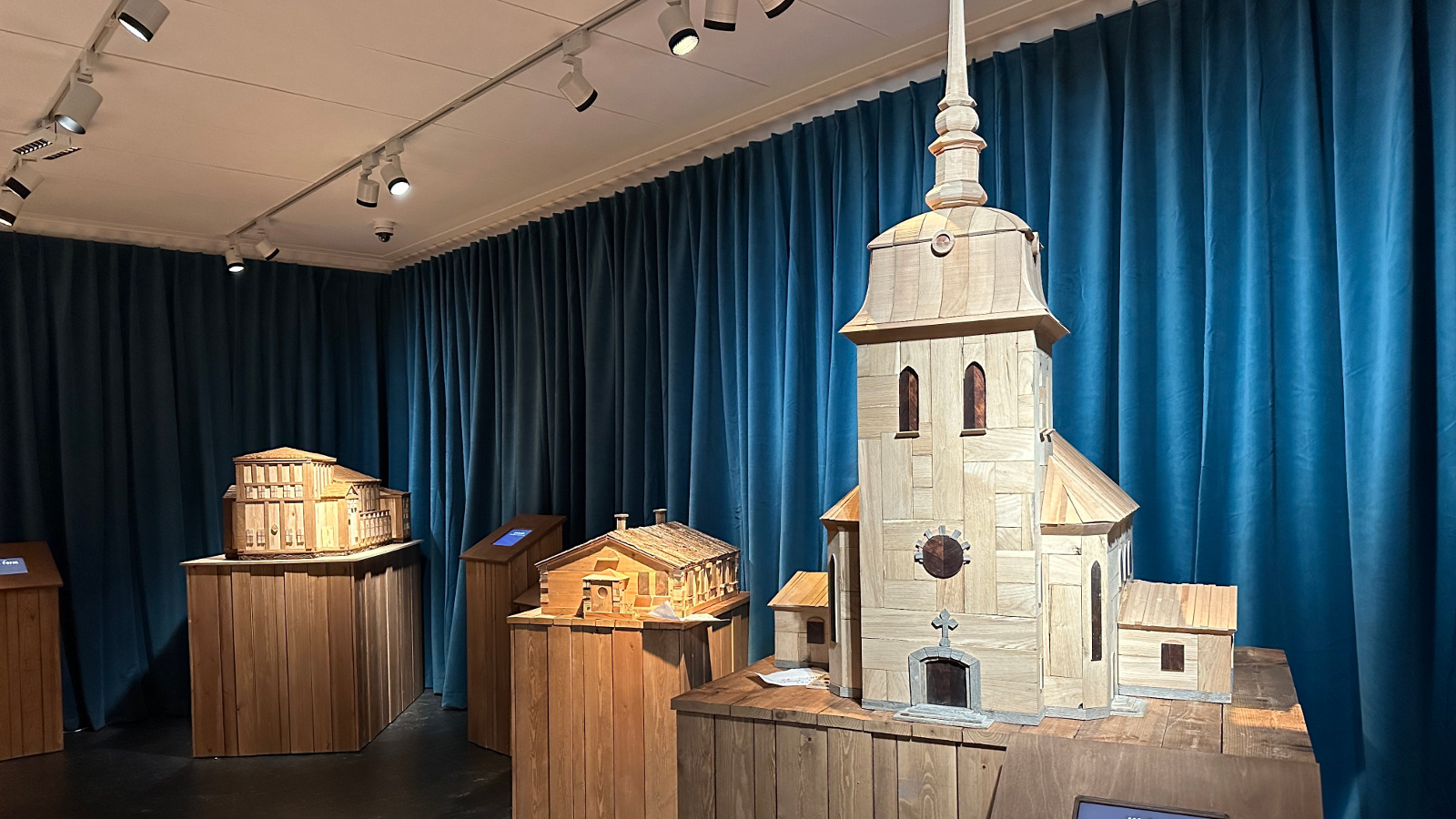 Kuvassa on siniverhoisessa näyttelytilassa puujalustojen päällä puisia pienoismalleja vanhoista rakennuksista. Oikealla etummaisena on Mäntän kirkko.