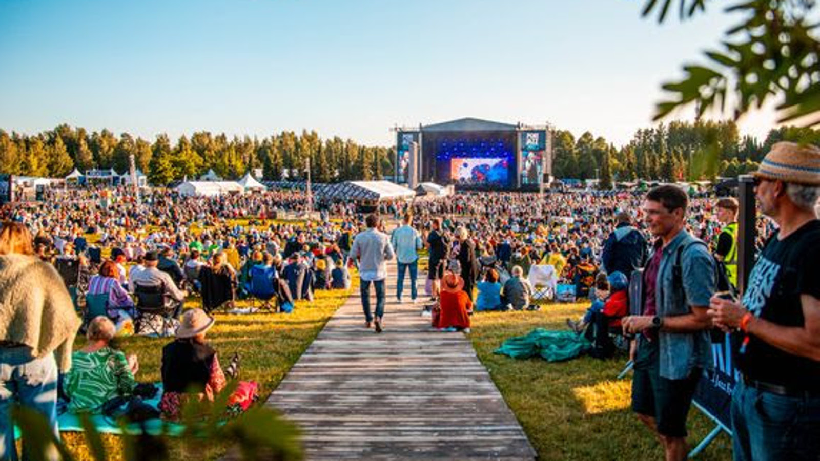 Kuvassa on takana Porin Kirjurinluodon esiintyjäteltta ja etualalla on yleisöä.  Keskellä on puulautapolkua.  Ilma on kesäinen ja on sininen taivas.