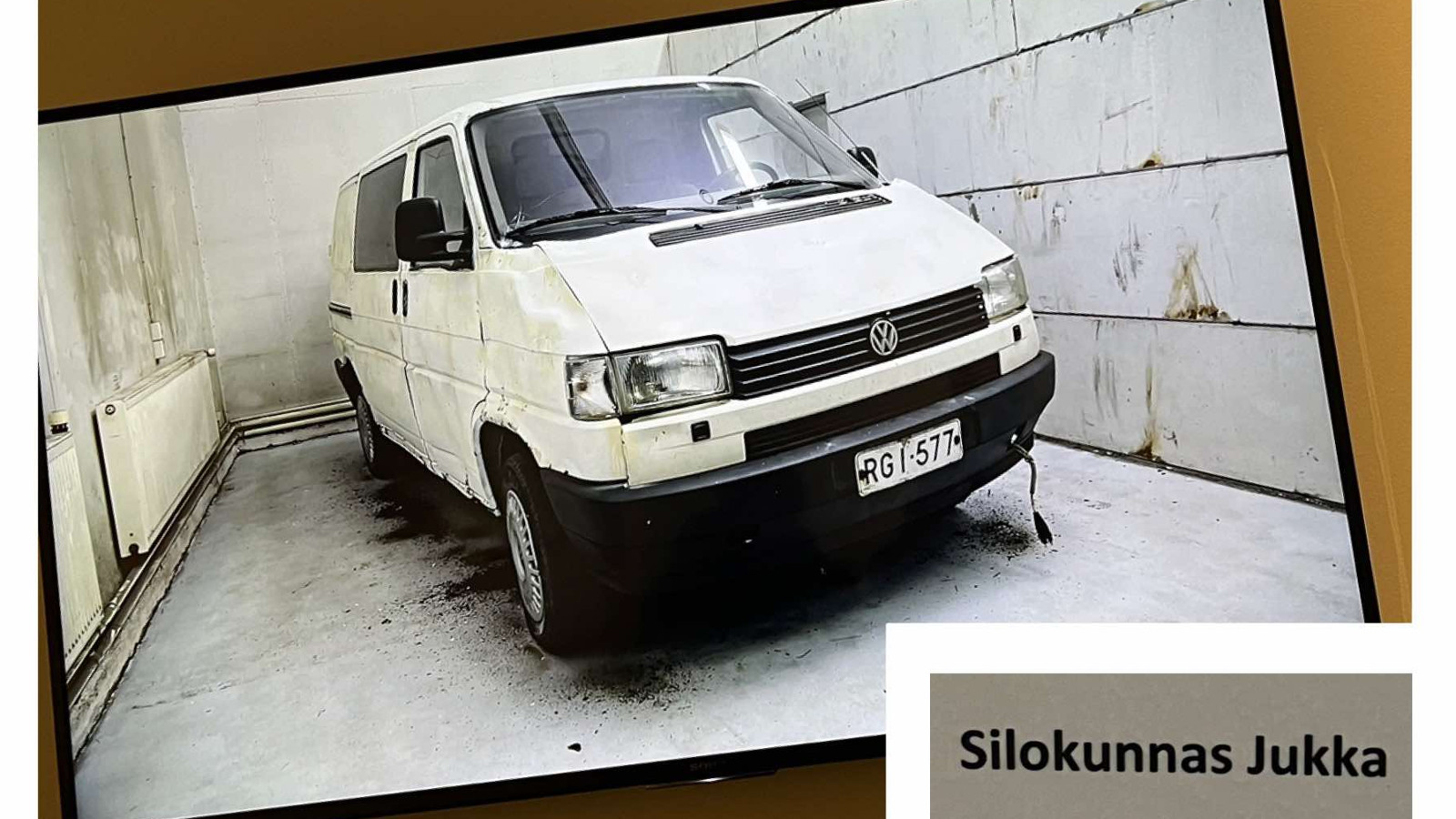 Kuvassa on vinosti kuva Volkswagen Transporterista vaaleassa tallissa. Alla on lokerossa nimi Silokunnas Jukka.