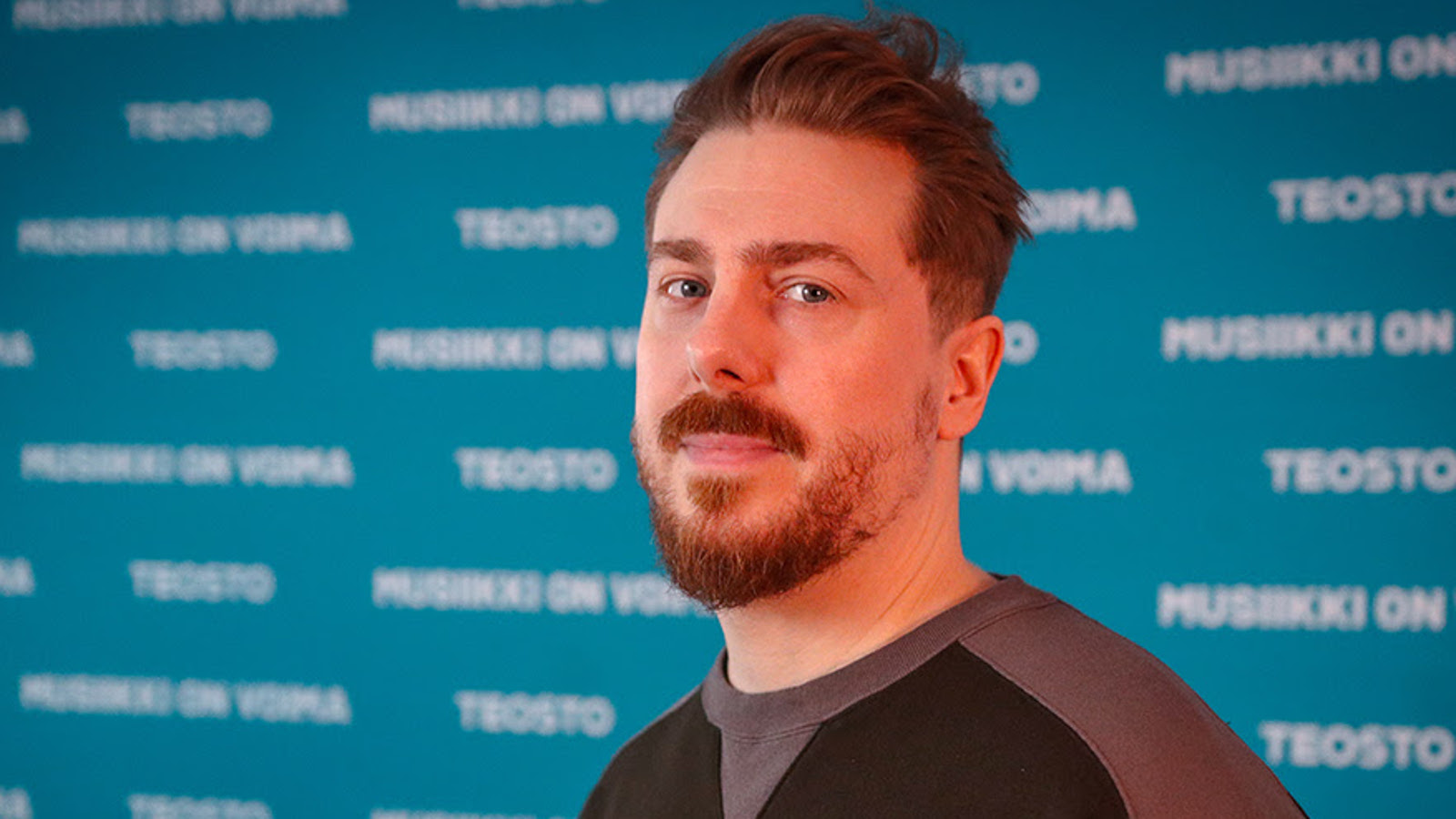 Kuvassa on Kridlokk ja hänestä on puolivartalokuva. Hänellä ruskehtavat lyhyehköt hiukset ja leukaparta. Taustalla on sinistä seinää ja siinä on valkoista himmeää tekstiä.